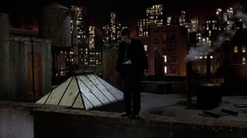 Movie still from “Little Shop of Horrors” (1986), directed by Frank Oz – A man in a suit standing in front of a building at night; Wide shot, Low angle