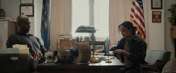 Movie still from “Little Woods” (2018), directed by Nia DaCosta – A person sitting at a desk with a laptop; Medium shot, High angle