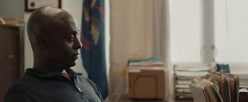 Movie still from “Little Woods” (2018), directed by Nia DaCosta – A man sitting in front of a bunch of papers; Close Up shot, Over the shoulder angle