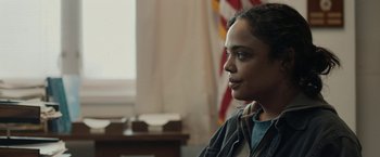 Movie still from “Little Woods” (2018), directed by Nia DaCosta – A woman sitting in front of an american flag in a room; Close Up shot, Over the shoulder angle