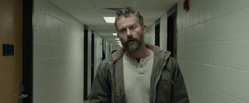 Movie still from “Little Woods” (2018), directed by Nia DaCosta – A man with a spiky beard standing in a hallway; Medium shot, Over the shoulder angle