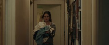 Movie still from “Little Woods” (2018), directed by Nia DaCosta – A woman holding a bunch of laundry in a room; Medium shot, Over the shoulder angle