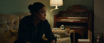 Movie still from “Little Woods” (2018), directed by Nia DaCosta – A woman sitting on a bed in a room with a piano; Medium shot, Over the shoulder angle