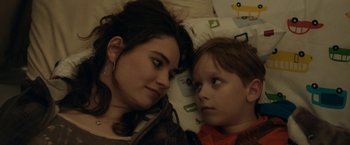 Movie still from “Little Woods” (2018), directed by Nia DaCosta – A woman and a child laying in bed together; Close Up shot, Overhead angle