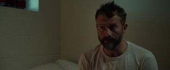 Movie still from “Little Woods” (2018), directed by Nia DaCosta – A man sitting in a room with a beard; Close Up shot, Over the shoulder angle