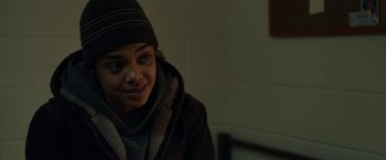 Movie still from “Little Woods” (2018), directed by Nia DaCosta – A young man wearing a brown jacket and a black hat; Close Up shot, Over the shoulder angle