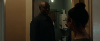 Movie still from “Little Woods” (2018), directed by Nia DaCosta – A man standing in front of a mirror in a room; Medium shot, Over the shoulder angle