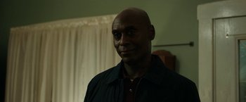 Movie still from “Little Woods” (2018), directed by Nia DaCosta – A man with a bald head is smiling for the camera; Close Up shot, Over the shoulder angle