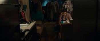 Movie still from “Little Woods” (2018), directed by Nia DaCosta – A woman sitting at a table reading a book; Wide shot, High angle