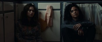 Movie still from “Little Woods” (2018), directed by Nia DaCosta – Two women sitting next to each other in front of a refrigerator; Medium shot, Low angle
