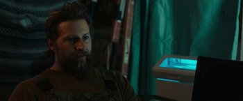 Movie still from “Little Woods” (2018), directed by Nia DaCosta – A man with a beard sitting in front of a window; Close Up shot, Over the shoulder angle