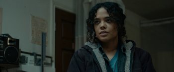 Movie still from “Little Woods” (2018), directed by Nia DaCosta – A woman with curly black hair standing in front of a door; Close Up shot, Over the shoulder angle