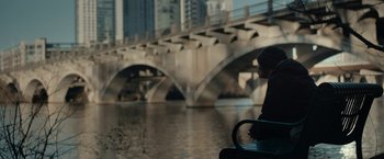 Movie still from “Little Woods” (2018), directed by Nia DaCosta – A person sitting on a bench near a body of water; Wide shot, Over the shoulder angle