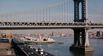 Movie still from “Live and Let Die” (1973), directed by Guy Hamilton – A large ship is under a bridge in the water; Extreme Wide shot, High angle