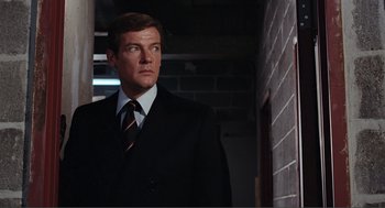 Movie still from “Live and Let Die” (1973), directed by Guy Hamilton – A person wearing a suit and tie; Medium shot, Low angle