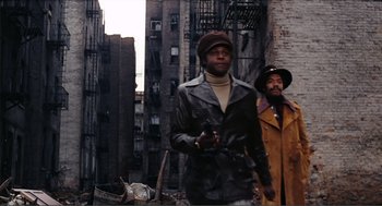 Movie still from “Live and Let Die” (1973), directed by Guy Hamilton – Two men are standing in the street in the city; Wide shot, Low angle