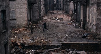 Movie still from “Live and Let Die” (1973), directed by Guy Hamilton – Two men are walking in an abandoned alley; Extreme Wide shot, High angle