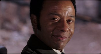 Movie still from “Live and Let Die” (1973), directed by Guy Hamilton – A person wearing a suit and tie; Close Up shot, Low angle