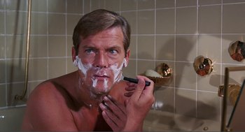 Movie still from “Live and Let Die” (1973), directed by Guy Hamilton – A man is shaving in the bathroom with a razor; Close Up shot, High angle