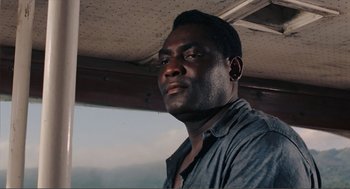 Movie still from “Live and Let Die” (1973), directed by Guy Hamilton – A man with a beard is looking at the camera; Close Up shot, Low angle