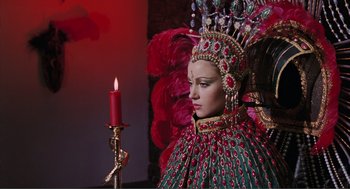 Movie still from “Live and Let Die” (1973), directed by Guy Hamilton – A woman dressed in a costume with a candle in front of it; Medium shot, Over the shoulder angle