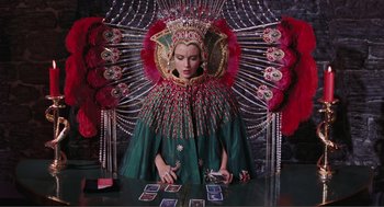 Movie still from “Live and Let Die” (1973), directed by Guy Hamilton – A woman in a green dress sitting in front of cards; Medium shot, Overhead angle