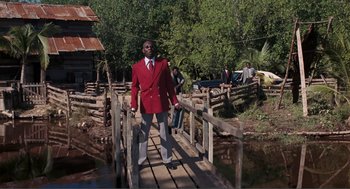 Movie still from “Live and Let Die” (1973), directed by Guy Hamilton – A man in a red jacket standing on a wooden bridge; Wide shot, Low angle