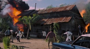 Movie still from “Live and Let Die” (1973), directed by Guy Hamilton – A group of people standing in front of a burning house; Extreme Wide shot, High angle