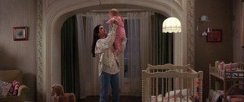 Movie still from “Labyrinth” (1986), directed by Jim Henson – A woman holding a baby up in the air in a room; Medium shot, Low angle