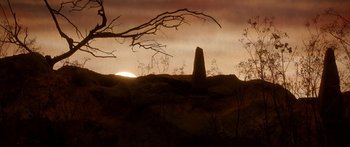 Movie still from “Labyrinth” (1986), directed by Jim Henson – The sun is setting behind a large stone monument; Extreme Wide shot, Low angle