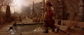 Movie still from “Labyrinth” (1986), directed by Jim Henson – A man in a costume standing in front of a rock wall; Wide shot, High angle