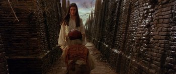 Movie still from “Labyrinth” (1986), directed by Jim Henson – A young woman is walking down a path with a backpack; Medium shot, Over the shoulder angle