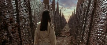Movie still from “Labyrinth” (1986), directed by Jim Henson – A woman walking down a brick path in a white robe; Wide shot, Low angle