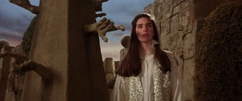 Movie still from “Labyrinth” (1986), directed by Jim Henson – A young woman standing in front of a stone wall; Close Up shot, Over the shoulder angle