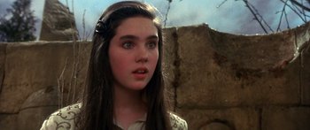 Movie still from “Labyrinth” (1986), directed by Jim Henson – A young girl with long dark hair looking at the camera; Close Up shot, Over the shoulder angle