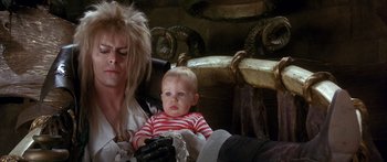 Movie still from “Labyrinth” (1986), directed by Jim Henson – Jareth the goblin king and his baby jareth; Medium shot, Overhead angle