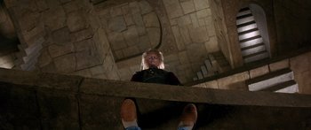 Movie still from “Labyrinth” (1986), directed by Jim Henson – A person sitting on the ground in front of a stone wall; Wide shot, Low angle