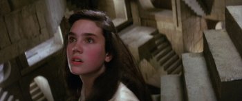 Movie still from “Labyrinth” (1986), directed by Jim Henson – A young woman with long dark brown hair looking up; Close Up shot, Over the shoulder angle