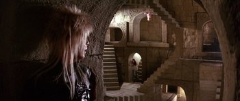 Movie still from “Labyrinth” (1986), directed by Jim Henson – A woman in a black outfit standing inside a castle; Wide shot, Over the shoulder angle