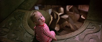 Movie still from “Labyrinth” (1986), directed by Jim Henson – A young child sitting on the floor of a building; Wide shot, High angle