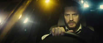 Movie still from “Locke” (2013), directed by Steven Knight – A person in a car holding a steering wheel; Close Up shot, Over the shoulder angle