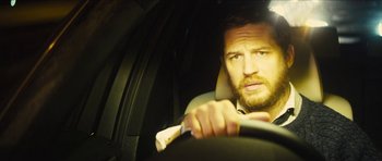 Movie still from “Locke” (2013), directed by Steven Knight – A person in a car holding a steering wheel; Close Up shot, Over the shoulder angle