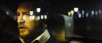 Movie still from “Locke” (2013), directed by Steven Knight – A man sitting in the back seat of a car; Close Up shot, Over the shoulder angle
