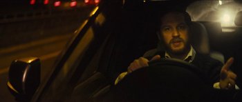 Movie still from “Locke” (2013), directed by Steven Knight – A man sitting in the driver's seat of a car at night; Close Up shot, Over the shoulder angle