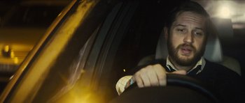 Movie still from “Locke” (2013), directed by Steven Knight – A man in a suit driving a car at night; Close Up shot, Low angle