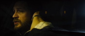 Movie still from “Locke” (2013), directed by Steven Knight – A blurry image of a person's legs and arms; Close Up shot, Over the shoulder angle