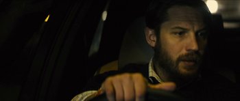 Movie still from “Locke” (2013), directed by Steven Knight – A person in a car holding a steering wheel; Close Up shot, Over the shoulder angle