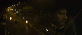 Movie still from “Locke” (2013), directed by Steven Knight – A blurry picture of a street at night; Wide shot, Over the shoulder angle