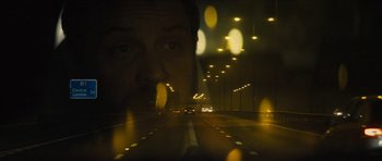 Movie still from “Locke” (2013), directed by Steven Knight – A man driving a car on a highway at night; Close Up shot, Over the shoulder angle