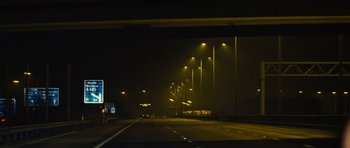 Movie still from “Locke” (2013), directed by Steven Knight – A night time view of a highway with street lights; Extreme Wide shot, Low angle